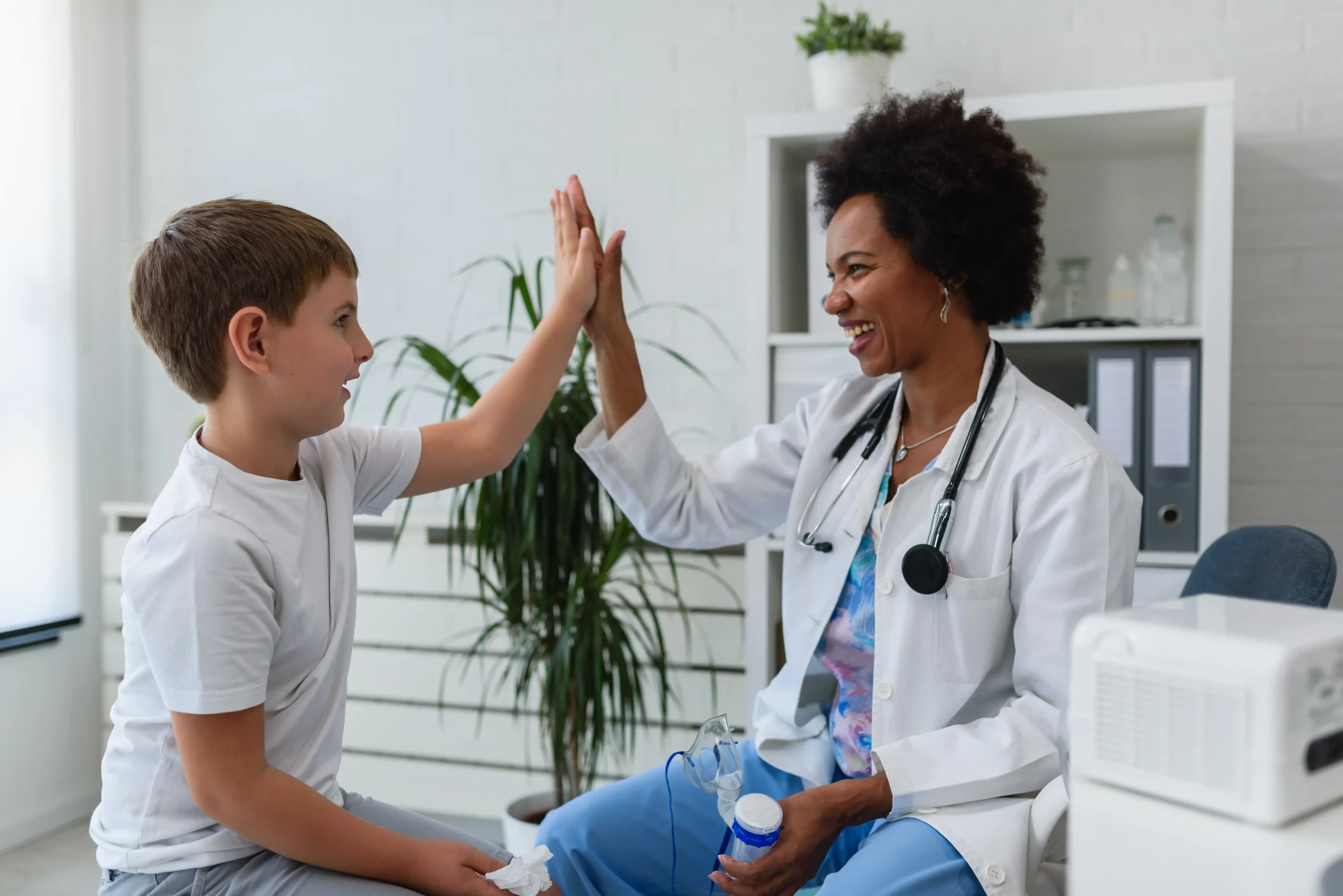 Doctor high fives young boy as he finished his check up