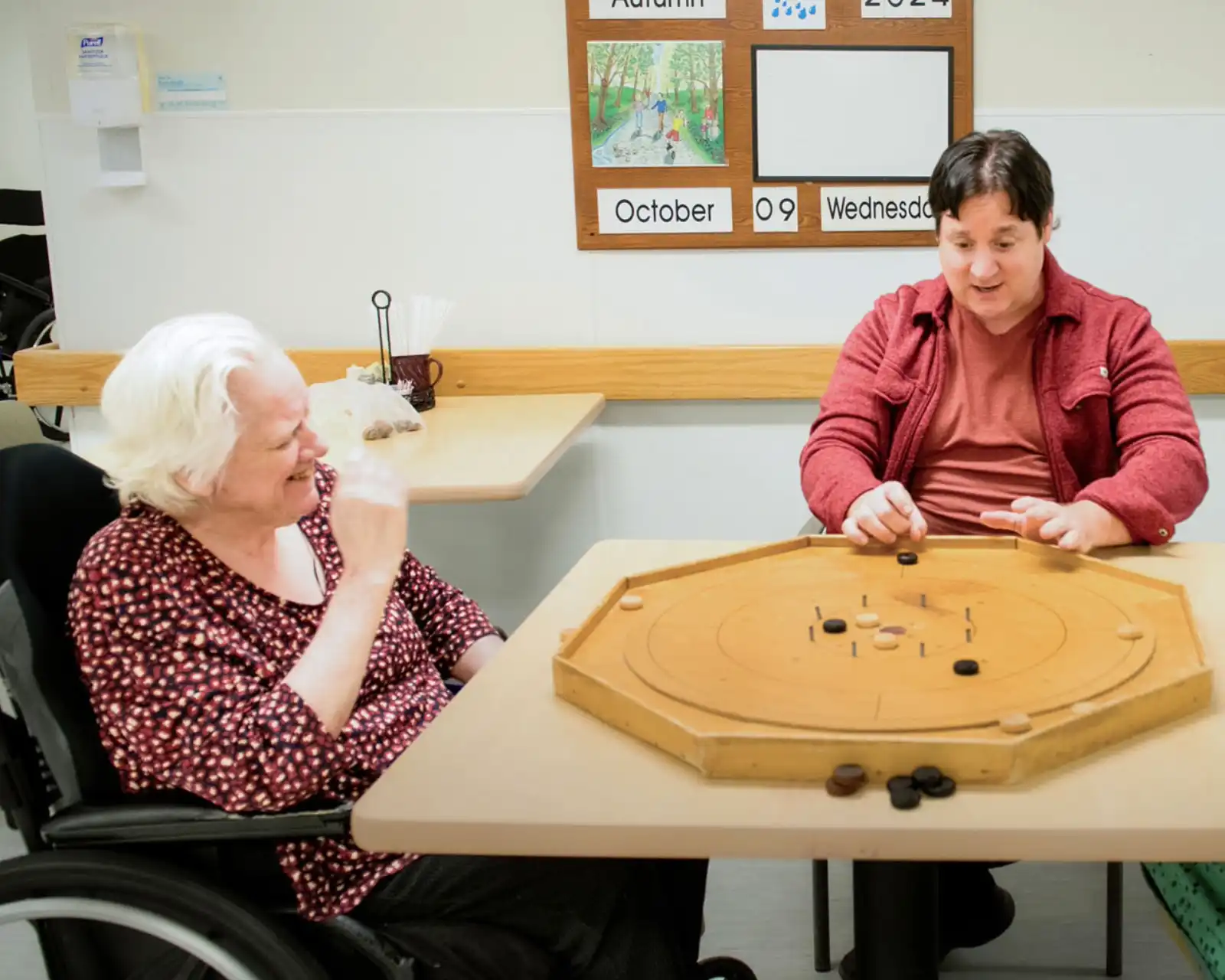 Volunteer sitting at a table with residents of the Golden Plough lodge Long-Term Care Home